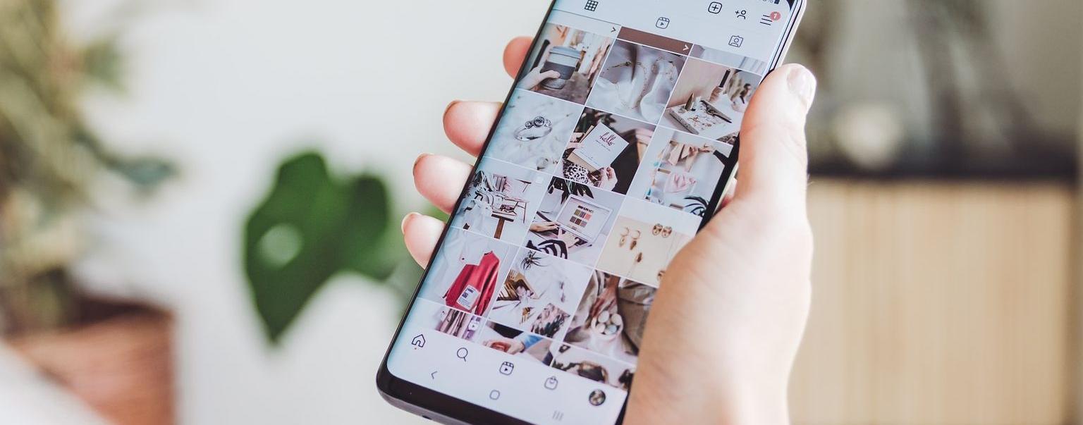 Une main tenant un téléphone dans lequel on aperçoit une page Instagram avec de jolies photos professionnelles